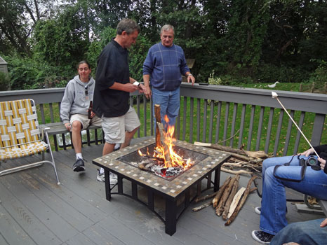 Brothers trying to make a teepee over the campfire 