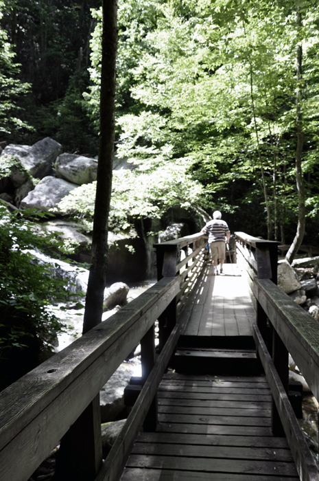 Lee Duquette on a bridge overlook a small cascade of water