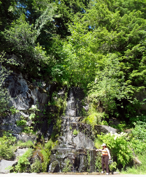 Karen Duquette feels the temperature of a cascade of water by the roadside