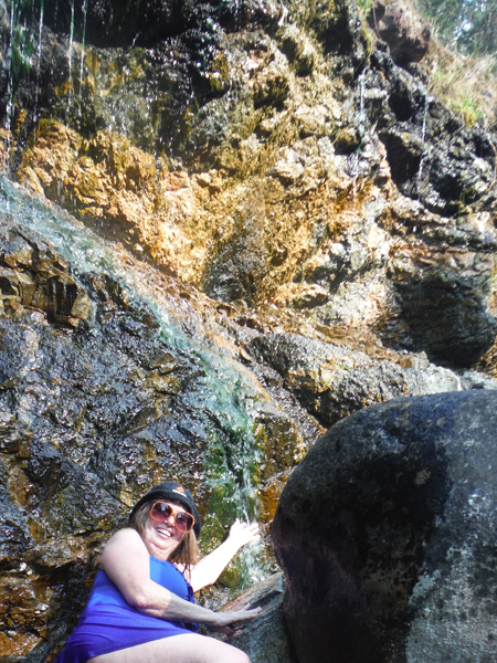 The hot water sprinkles down the cliffs like a gentle waterfall as Karen enjoys the experience.