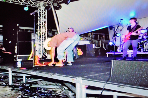 Neil McCoy removing boots and socks on stage