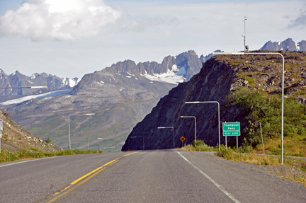 Snow poles by the road and the sign for Thompson's Pass
